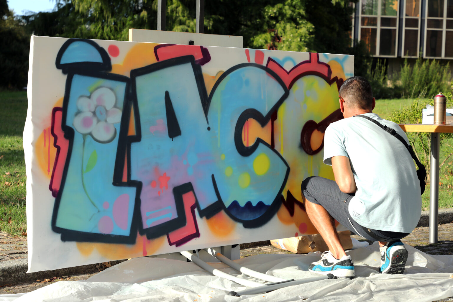 graffeur tagguant à la bombe sur une toile les lettres de Lac c