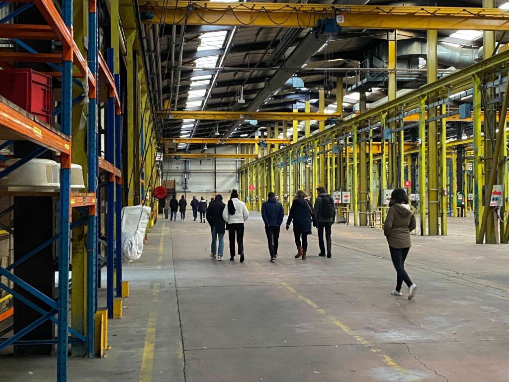 Groupe de personnes marchant dans une halle industrielle du site Etape 22D