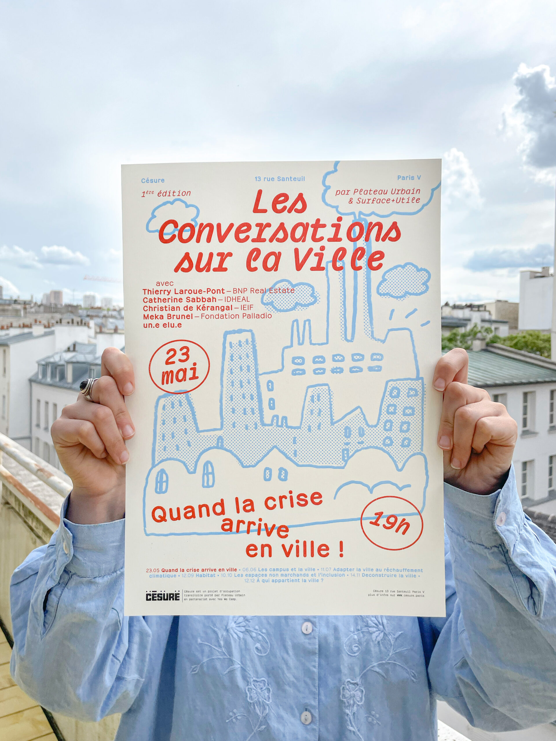 photographie d'une affiche, tenue par deux mains, présentant l'évènement Les Conversations sur la Ville.